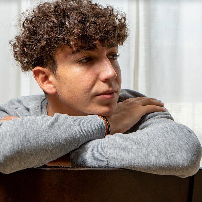 Man with curly perm hairstyle showcasing natural texture and volume at BarberNBar in Cheltenham.