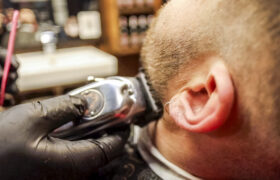 Close-up of a barber using clippers to trim hair around a client’s ear